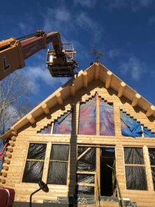 A lull machine lifts roof system materials on a Katahdin Cedar Log Home